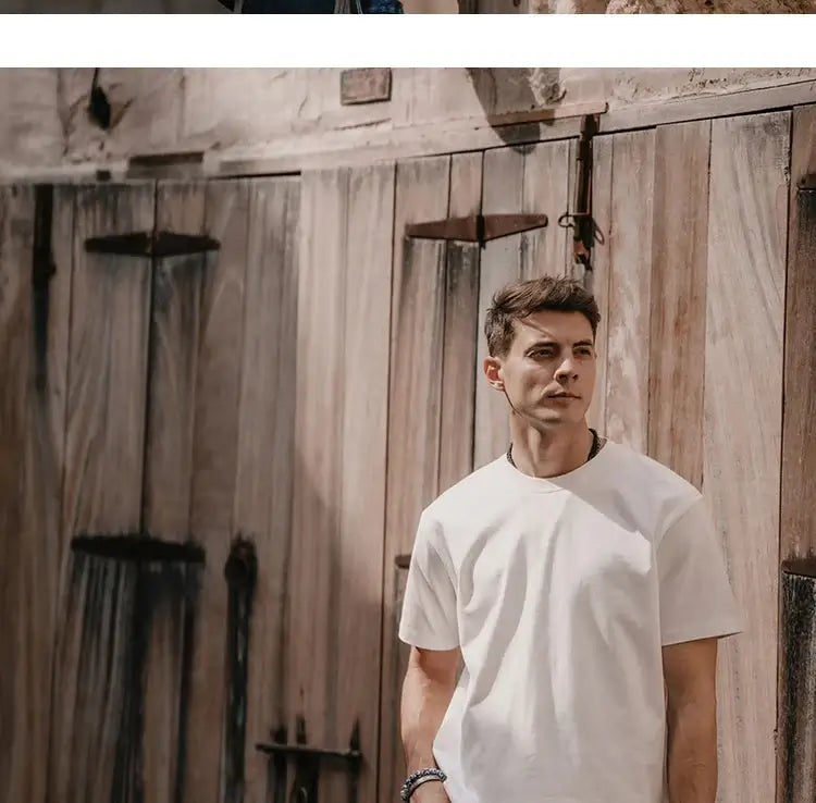 Man wearing a Superdry vintage t-shirt leaning against wooden doors, showcasing retro style and comfort.